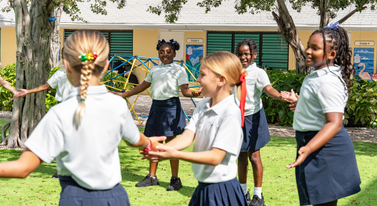 Primary students playing group games outdoors during a school holiday camp program.